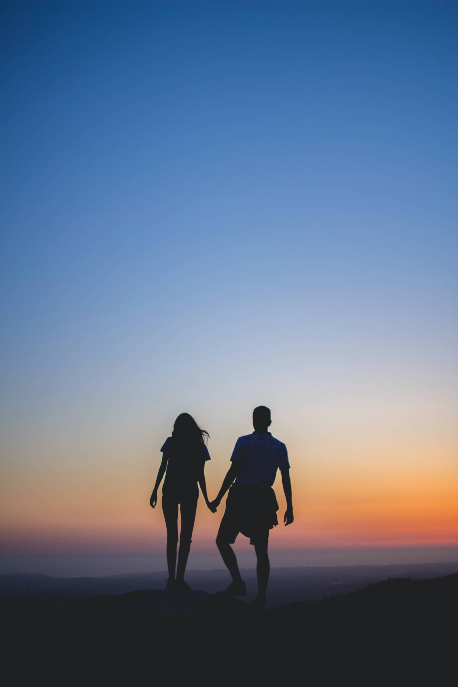 Are you falling out of love? Image of couple holding hands walking with a sunset in the background.